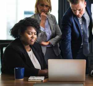 woman sitting in front of table beside man leaning on laptop